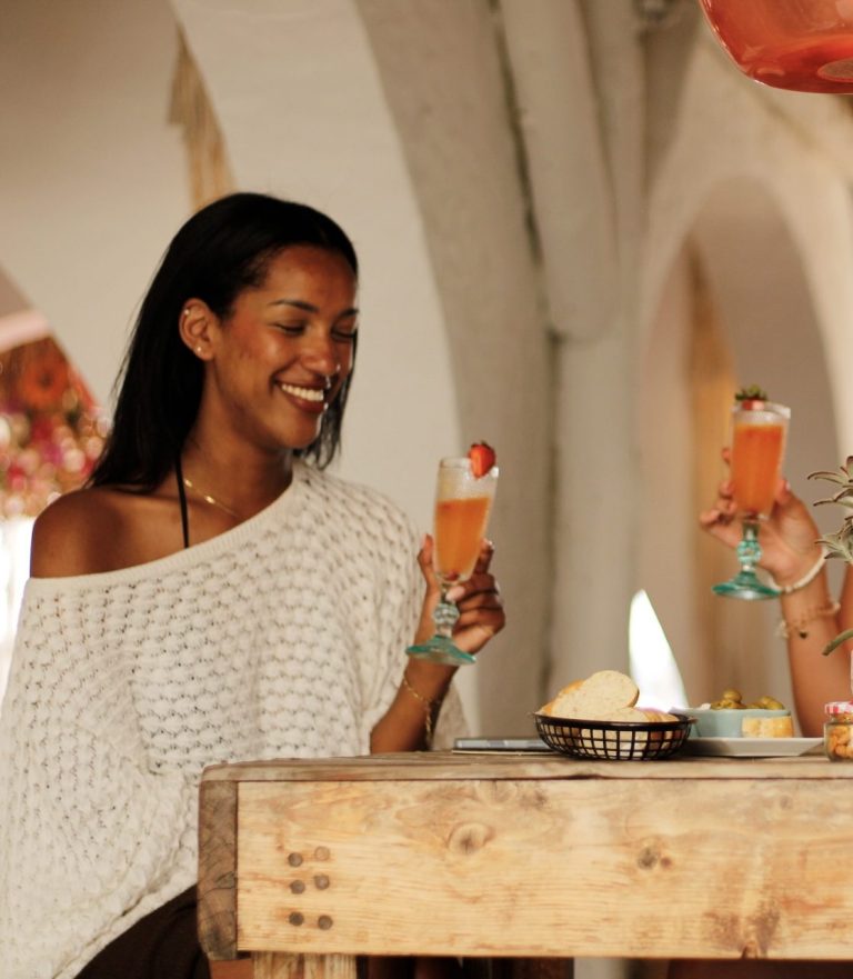 Gast lacht met een cocktail in de hand bij Beachcafé Tulp